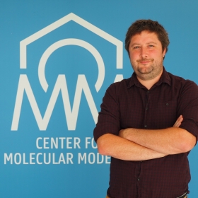 A figure of Jelle Vekeman against the backdrop of the logo of the Center for Molecular Modeling.